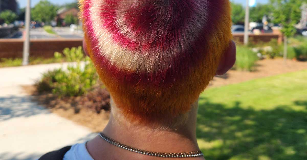 Young skateboarder with bullseye dyed hair standing in park, representing the home arcade game trend.